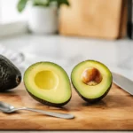 Avocado sicher auf einem Brett geschnitten mit Löffel und abgelegtem Küchenmesser